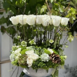 White roses and green succulents in a round gray vase
