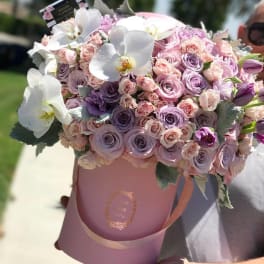 Pink and lavender rose bouquet in a pink hatbox with white orchids