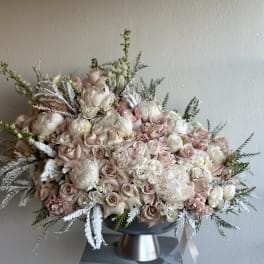 Large blush and white floral arrangement in a pedestal vase
