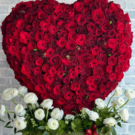 Heart-shaped red rose arrangement with white flowers at the base
