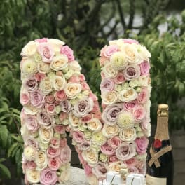 Pastel rose floral arrangement shaped like the number 18 with champagne and gift boxes