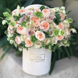 Blush and cream roses arranged in a white hat box