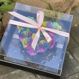 Rainbow roses in a clear gift box tied with a pink ribbon