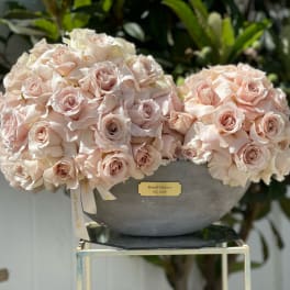 Two pale pink rose arrangements in a gray bowl vase