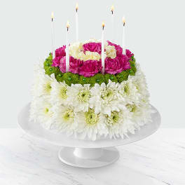 Round floral cake with white and pink flowers and tall candles