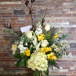 Tall bouquet of white and yellow flowers in a glass vase