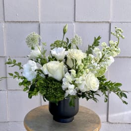 White roses and white blooms arranged in a black vase