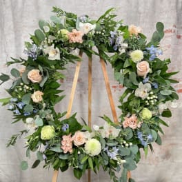 Floral wreath with pastel roses and mixed blooms on a wooden stand