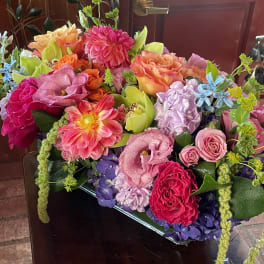 Colorful mixed bouquet in a glass vase with roses, dahlias, and orchids