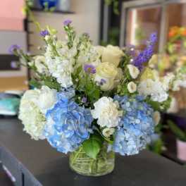 Blue and white flower arrangement in a clear glass vase