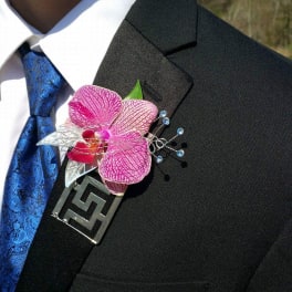 Pink orchid boutonniere pinned to a black suit jacket