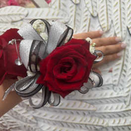 Red rose corsage with silver ribbon on a wrist