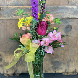 Mixed bouquet in a glass vase with pink, purple, and yellow flowers