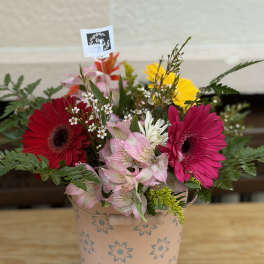 Mixed gerbera daisy bouquet in a pink floral tin