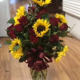 Bouquet of red roses and yellow sunflowers in a glass vase