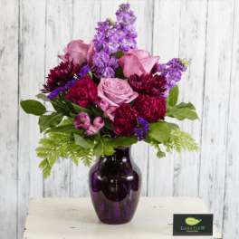 Pink and purple mixed bouquet in a dark glass vase