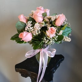 Pink roses in a glass vase with baby's breath and a pink ribbon