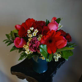 Red and pink mixed bouquet in a blue vase