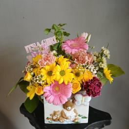 Colorful mixed bouquet in a decorative bear planter with a "IT'S A GIRL" sign
