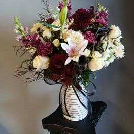 Mixed bouquet of white, pink, and burgundy flowers in a striped vase