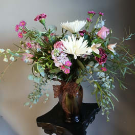 Mixed bouquet of pink and white flowers in a dark vase