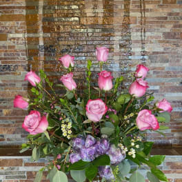 Pink roses arranged in a clear glass vase with greenery