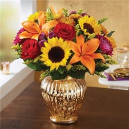 Bouquet of sunflowers, roses, and lilies in a gold vase