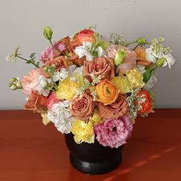 Mixed bouquet of pastel roses and carnations in a black vase