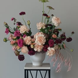 Loose bouquet of pink and cream flowers in a white vase