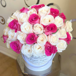 Round box of white and hot pink roses arranged tightly in a white hatbox container