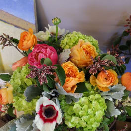Bouquet of orange and pink flowers with green hydrangeas and a white anemone