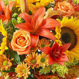 Orange lilies, roses, and sunflowers in a colorful bouquet