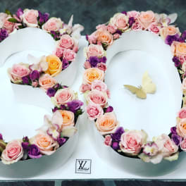 Floral arrangement shaped like the number 80 with pink, peach, and purple roses