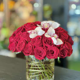 Red roses with white orchids in a glass vase