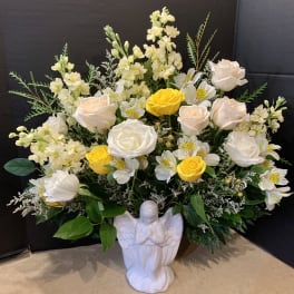 White and yellow rose arrangement in a white angel vase