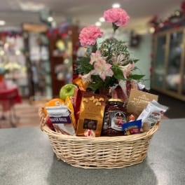 Gift basket with pink flowers and assorted snacks