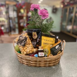 Gift basket with snacks and pink flowers in a woven basket