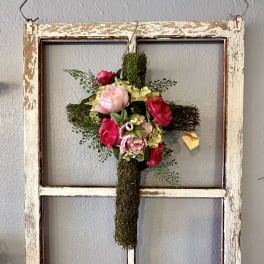 Floral cross with pink and red flowers on a rustic wooden frame