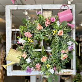 Floral wreath on a white window frame with two watering cans