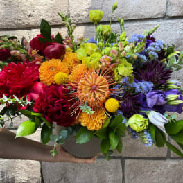 Colorful mixed bouquet in a round vase with red, orange, yellow, and purple blooms