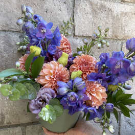 Colorful bouquet in a small gray vase with peach and purple flowers