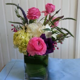 Pink and white flowers arranged in a clear glass vase.