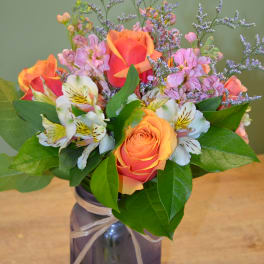 Orange roses and white alstroemeria in a blue glass vase