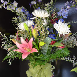 Mixed bouquet with pink lilies, white chrysanthemums, and blue flowers in a glass vase