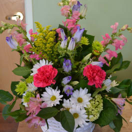Mixed bouquet in a white basket with pink, purple, and white flowers