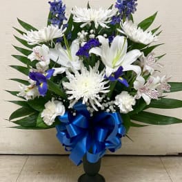 White lilies and chrysanthemums with blue flowers in a vase, tied with a blue ribbon