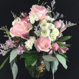 Pink roses and white flowers arranged in a glass vase