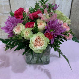 Bouquet of pink and purple flowers in a square glass vase