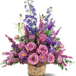 Pink roses and purple flowers arranged in a wicker basket