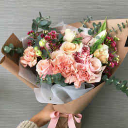 Hand-tied bouquet of blush roses and pink carnations with eucalyptus